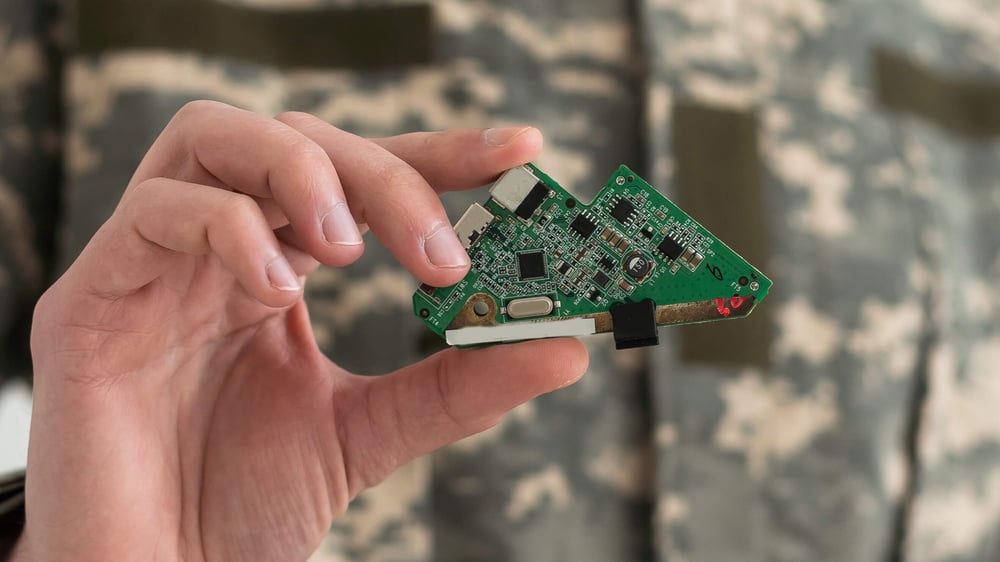 military personnel holding a printed circuit board 