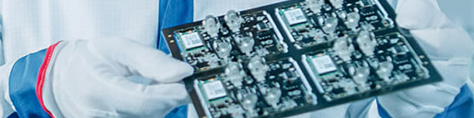 PCB with conformal coating being visually inspected by a QA engineer