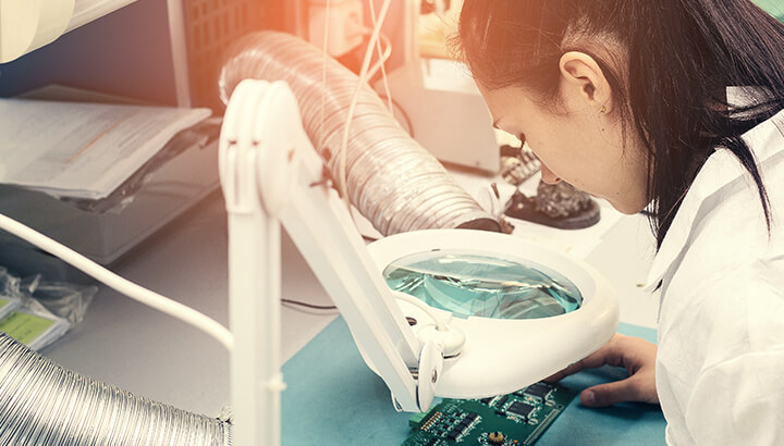 engineer observing PCB with equipment